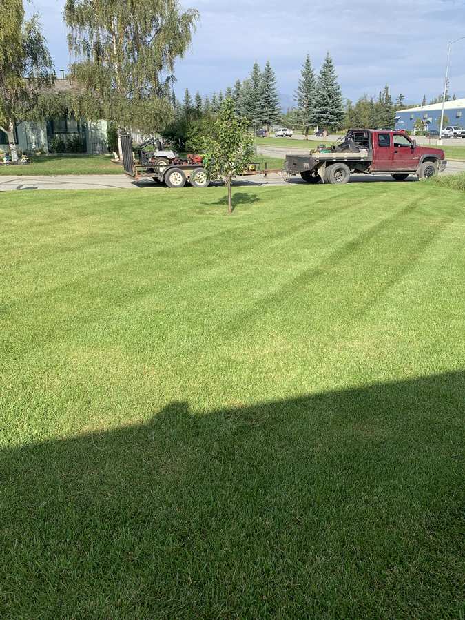 49th State Lawn & Snow work truck and mower trailer parked at a freshly striped Palmer, Alaska lawn