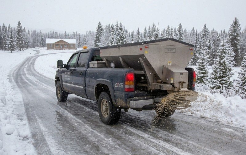 Sanding truck spreading traction sand on an icy road